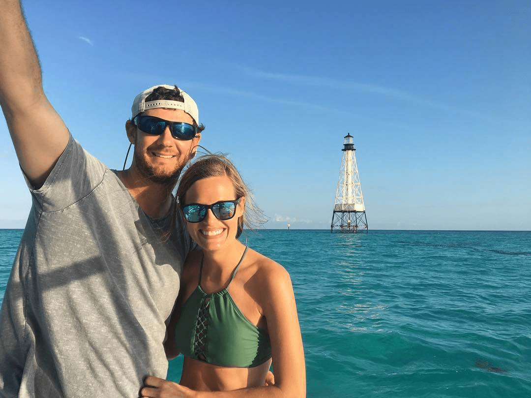 A private boat anchored near Alligator Lighthouse as seen from Islamorada, with clear blue water and the historic lighthouse in the background.